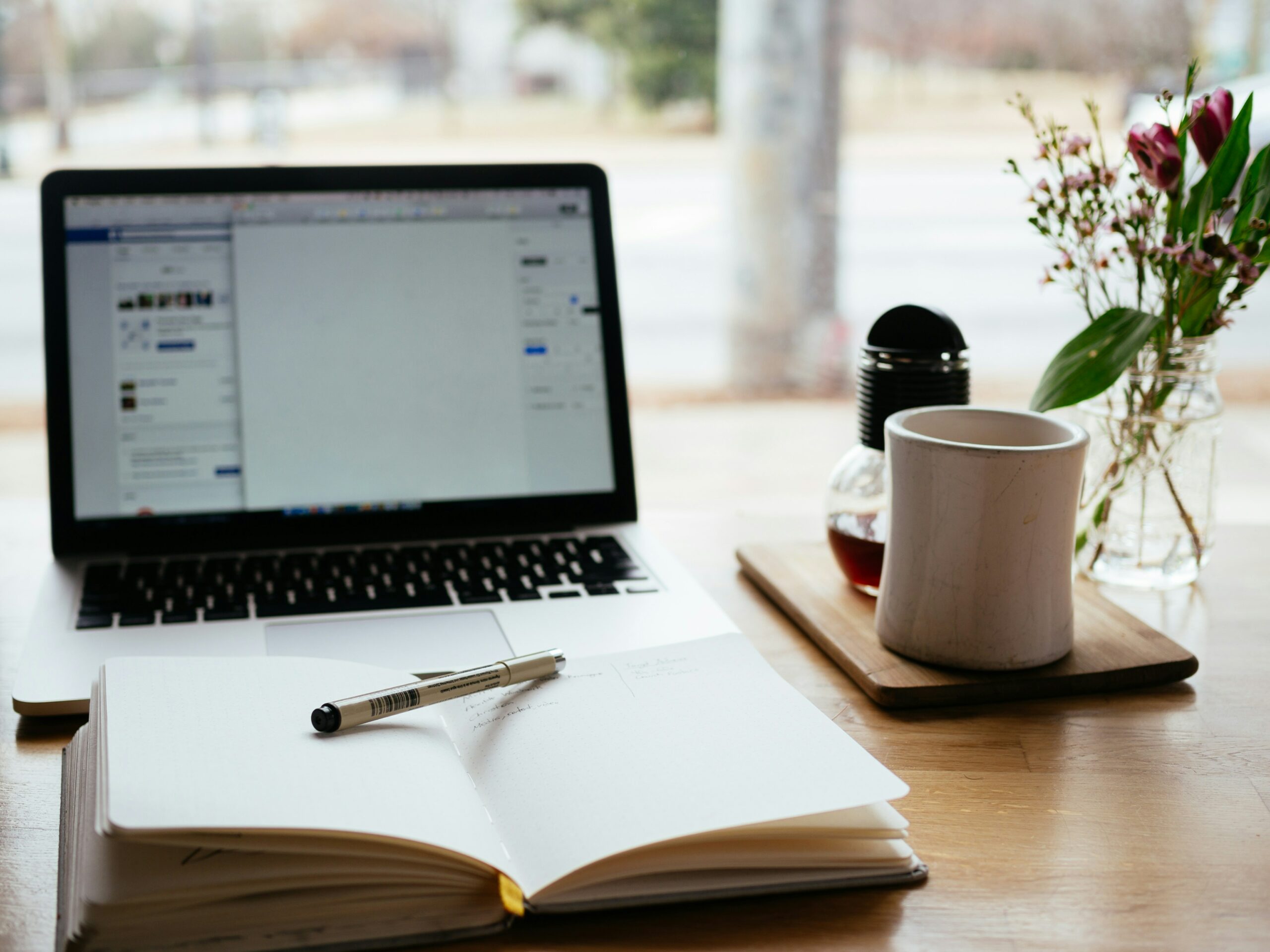 A clean workspace with a laptop and open notebook